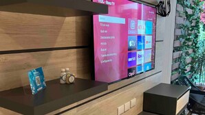 A modern interior with a large flat-screen TV mounted on a wooden wall displaying a TV menu. - Hana175 (Mexico City)