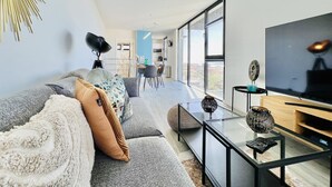 A modern living room with a sofa, TV, and glass coffee table. - Haus am Meer by Your Madeira Rentals (Paúl do Mar)