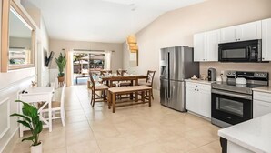 Una cocina moderna con electrodomésticos de acero inoxidable, un comedor con mesa y sillas de madera, y vistas al exterior.