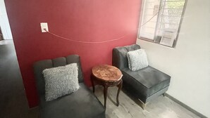 A room with two grey sofas, a small round wooden table, and a red accent wall.