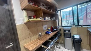 A kitchen area with a wooden countertop, a sink, a trash bin, and a window with a view of the outside.