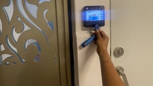 A hand using a blue card to interact with a digital lock on a door.