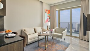 Une chambre d’hôtel moderne équipée d’un canapé, d’un fauteuil, d’une table à manger et offrant une vue sur la ville.
