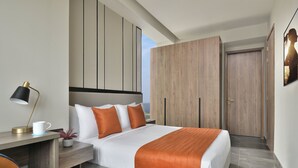 Une chambre d’hôtel moderne équipée d’un lit, d’un bureau avec une lampe, d’une chaise et d’une armoire.