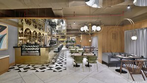 Un restaurant moderne doté d’un bar, de plusieurs espaces de restauration et d’un sol orné de motifs géométriques.