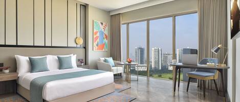A modern hotel room with a large bed, a desk, a chair, and a view of the city.