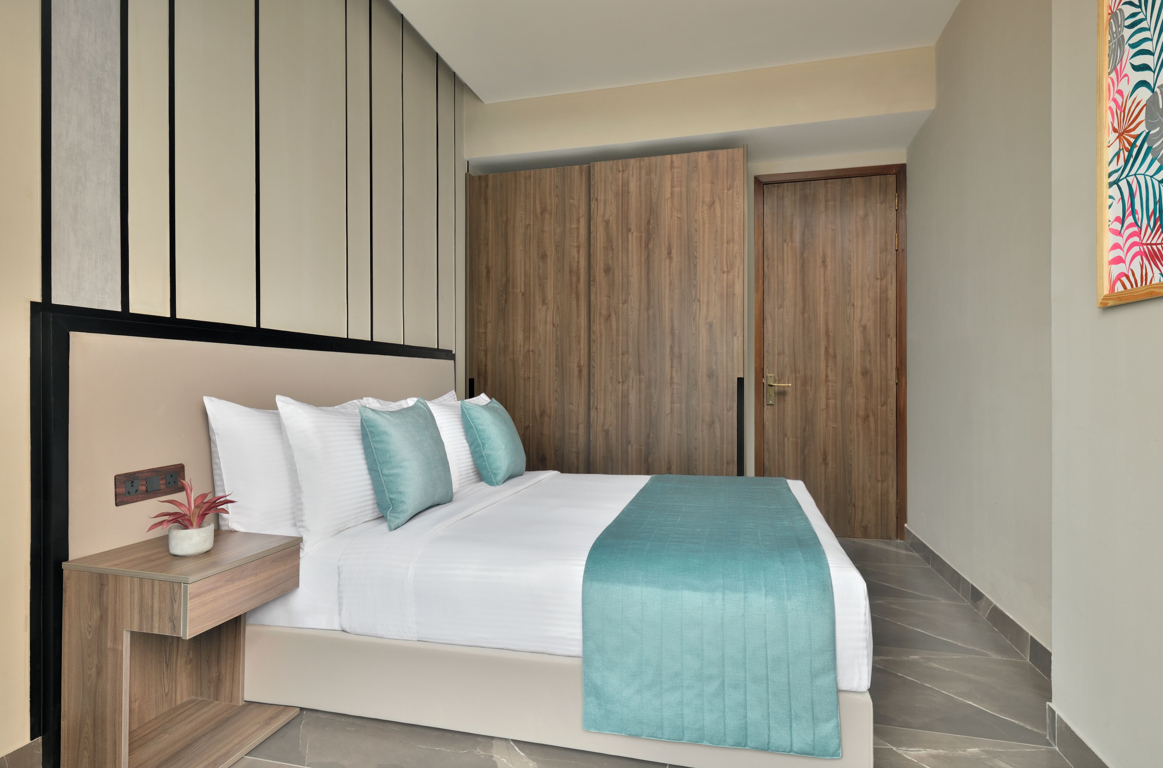 Ein modernes Schlafzimmer mit einem großen Bett, einem Holzschrank und einem kleinen Nachttisch mit einer Pflanze.