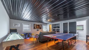 Un ampli saló amb una taula de futbolí, una taula de ping-pong i un sofà.
