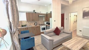 A modern living room with a sofa, a coffee table, and a dining area with a table and chairs. - Botanic Apartment Central-Parking-sleep3 (Liverpool)