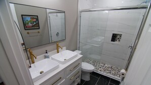 A bathroom with two sinks, a toilet, a shower, and a mirror. - The Capitol Inn - Destin Room - Queen bed (Tallahassee)