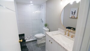 A modern bathroom with a shower, toilet, and sink.