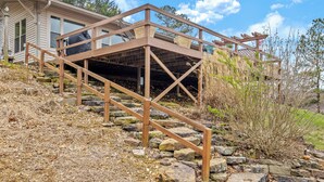 A house with a wooden staircase leading to a covered deck area.
