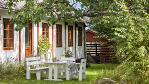 A white house with red window frames and a wooden fence in the background.