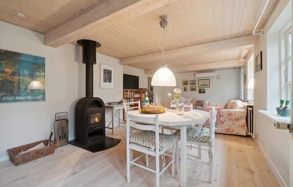 A cozy room with a fireplace, a dining table with chairs, a sofa, and a bookshelf.