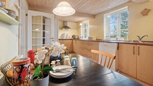 A kitchen with wooden cabinets, a black dining table, and a window providing natural light.