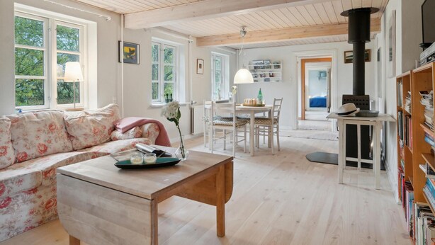 A cozy living room with a floral sofa, a wooden table, and a bookshelf.