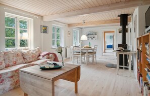 A cozy living room with a floral sofa, a wooden table, and a bookshelf.