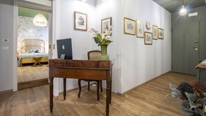 A room with a wooden floor, a desk, a chair, a bed, and framed pictures on the wall. - Epimonì B&b (Catania)