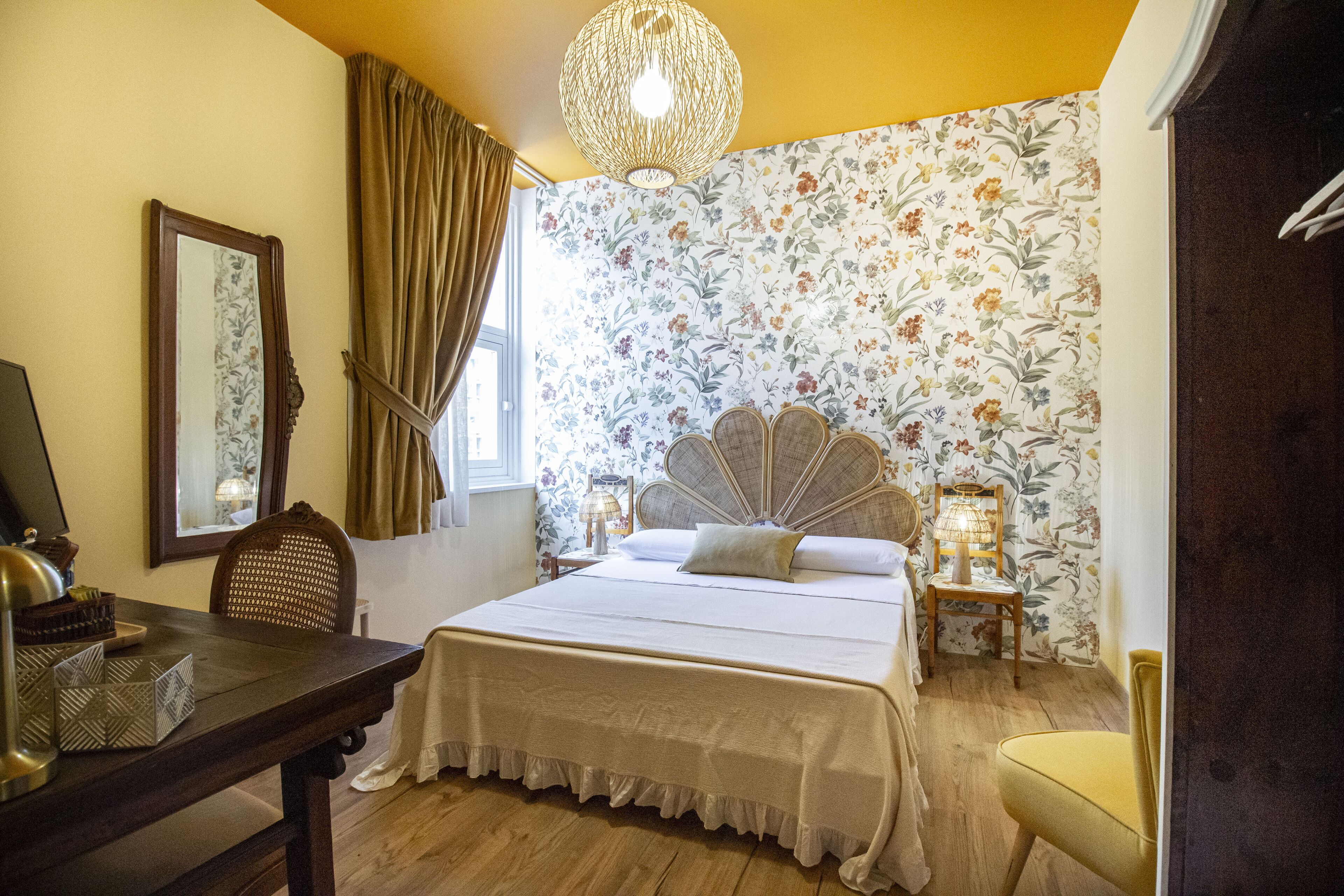 Un dormitorio con cama, escritorio, silla, lámpara y ventana con cortinas.