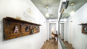 A hallway with a wooden shelf displaying various items, a sign reading "Epimoni B&B", and a mirror reflecting the hallway. - Epimonì B&b (Catania)