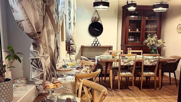 A dining area with a wooden table set for a meal, surrounded by chairs, and a cabinet in the background. - Epimonì B&b (Catania)