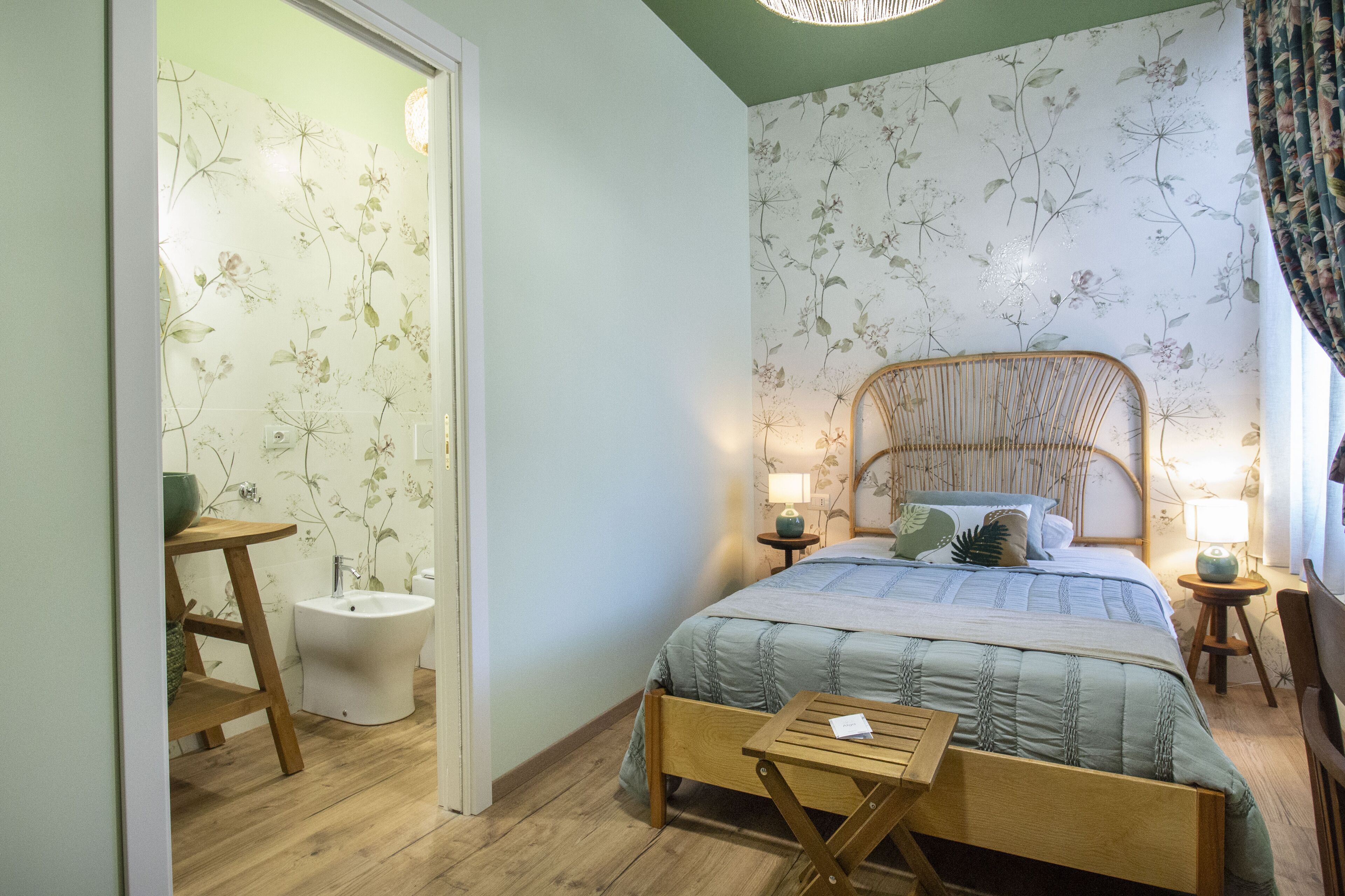 Un dormitorio con cama, mesitas de noche, una silla de madera, una mesita pequeña y un bidé.