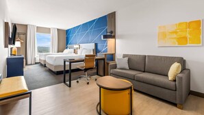 A hotel room with a bed, a sofa, a desk, and a chair. - Comfort Inn & Suites at Sanford Sports Complex (Sioux Falls)