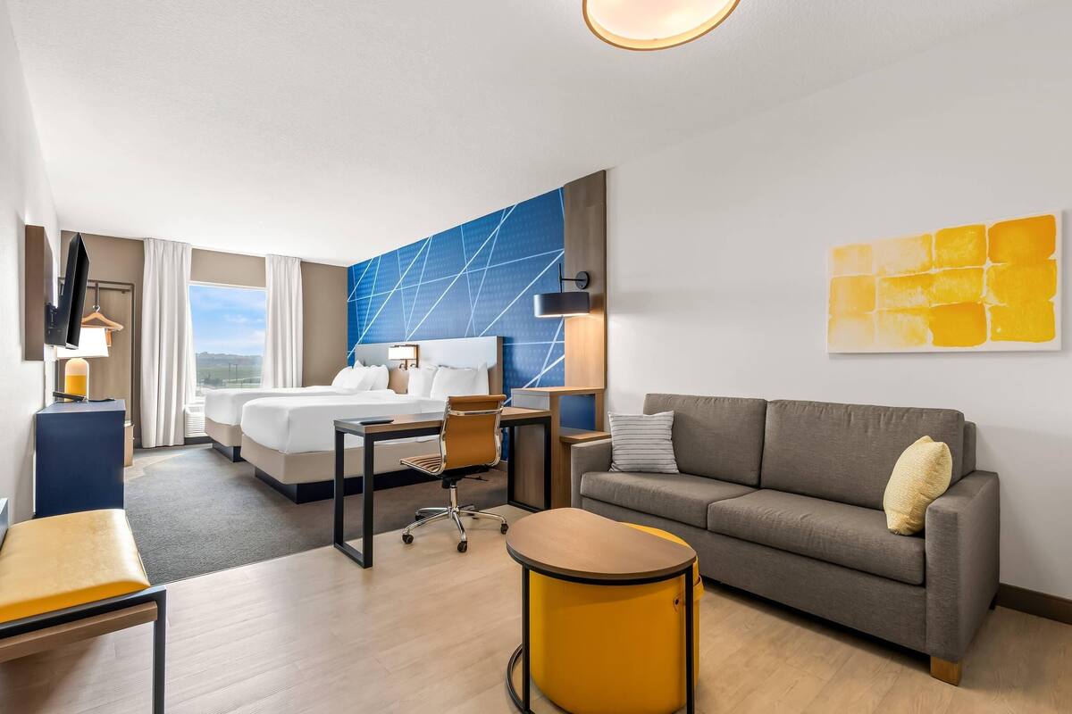A hotel room with a bed, a sofa, a desk, and a chair.