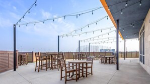 An outdoor patio area with tables and chairs, string lights, and a view of the city skyline. - Comfort Inn & Suites at Sanford Sports Complex (Sioux Falls)