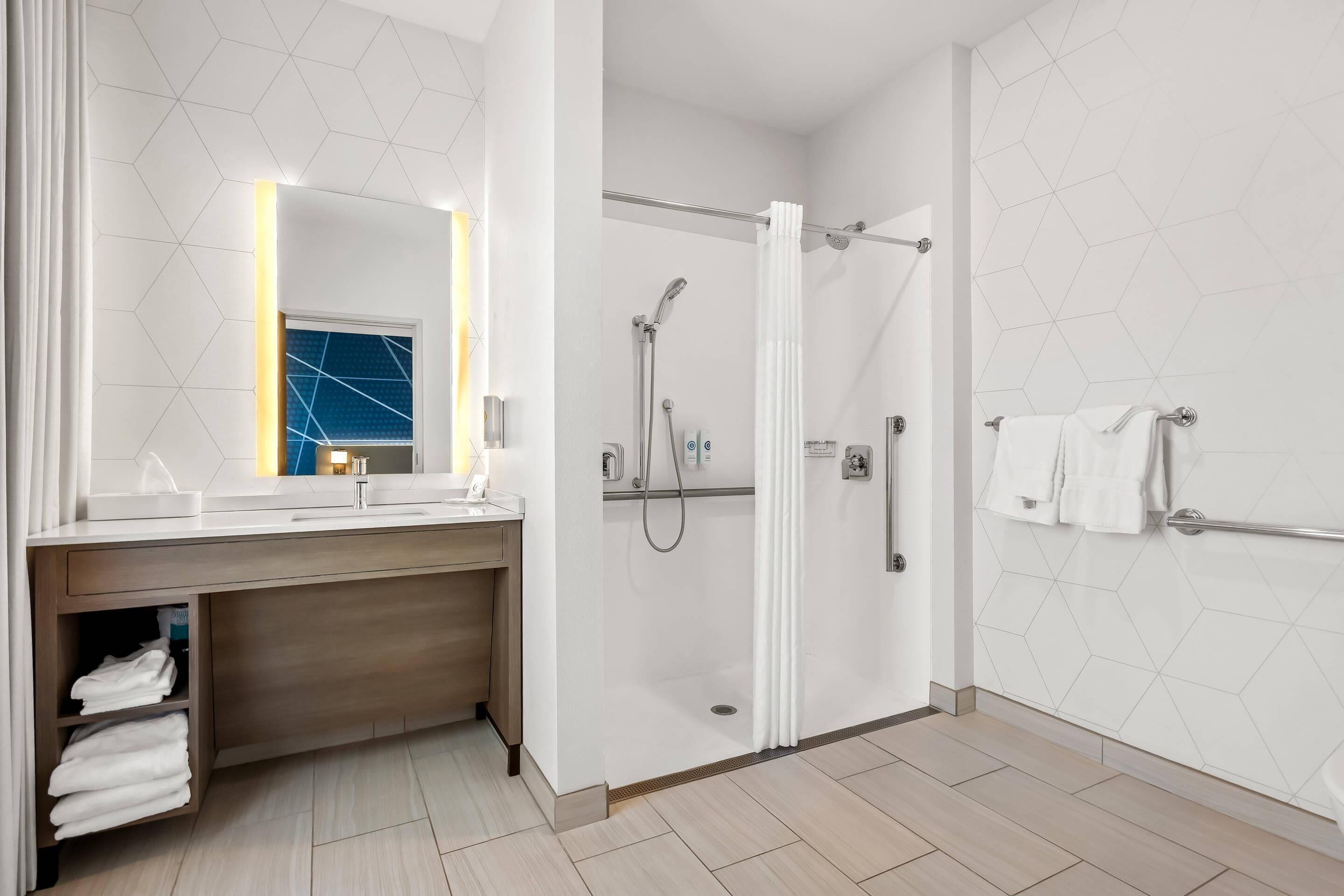A modern bathroom with a vanity, a shower, and a towel rack.