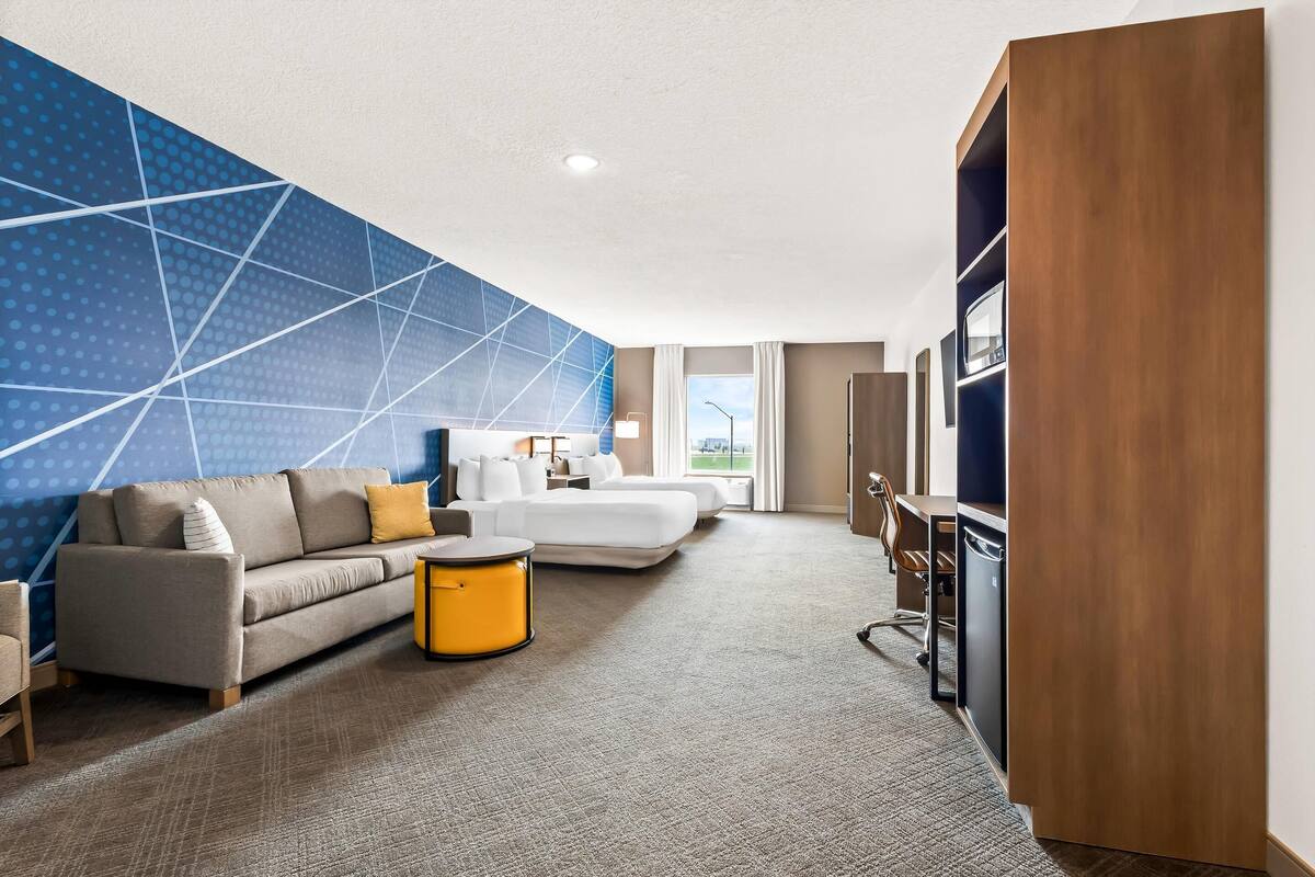 A hotel room with a sofa, a bed, a small table, and a TV.