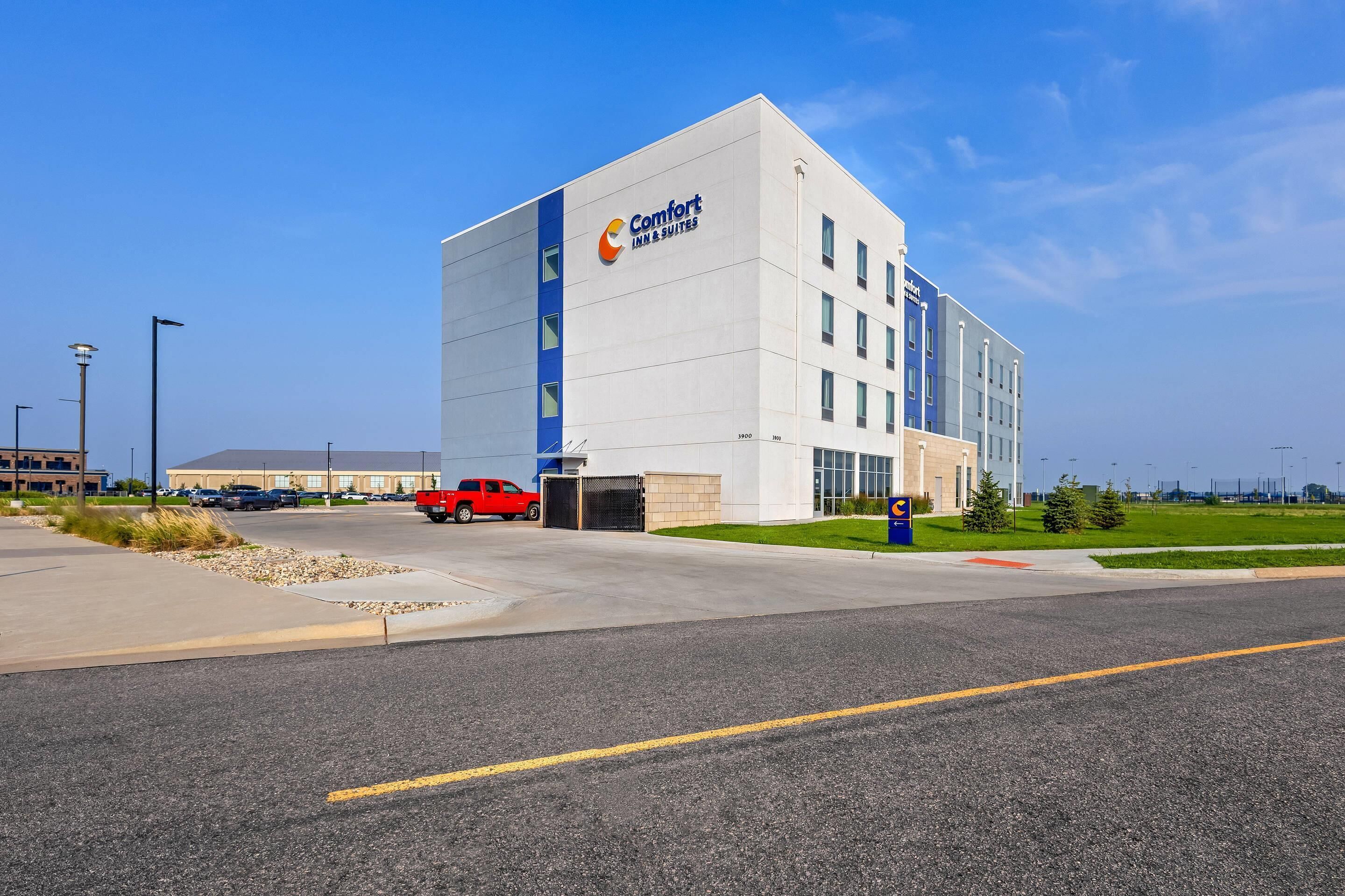 A modern building with a prominent Comfort Inn & Suites sign, featuring a clean, white facade with blue accents and multiple windows.