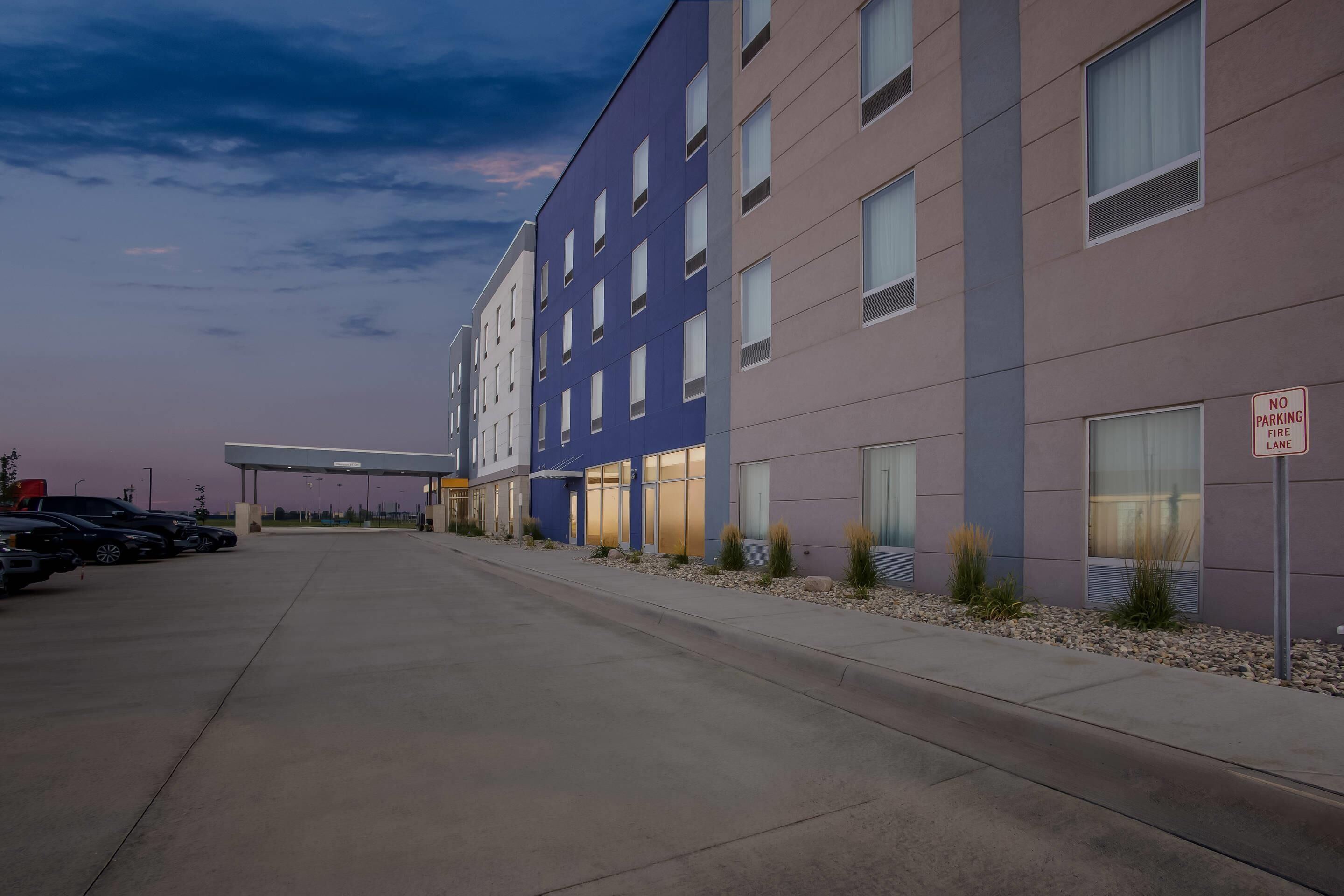 Een modern gebouw met een parkeerplaats en een bord met de tekst 'Brandveiligheidszone, geen parkeren'.