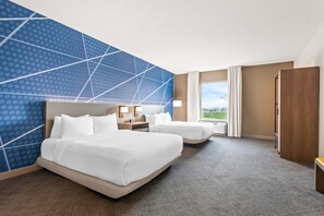 Quarto de hotel com duas camas, uma janela grande e vista para o exterior.