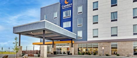 Un moderno edificio Comfort Inn & Suites con un acceso cubierto, ventanas amplias y un cielo despejado.