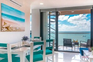 Enjoy ocean views from the large window in this stylish room, featuring a dining area with a table and vase of flowers.