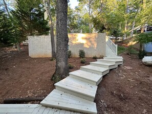 A wooden staircase leading up to a building with a stone wall. - Warluskee Luxury Lakefront Cottage w/ Hot Tub

 (Waleska)