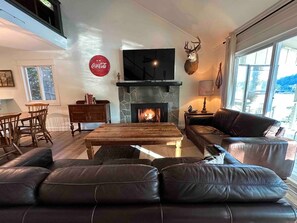 Una sala de estar con chimenea, sofás de cuero, una mesa de centro y un televisor.