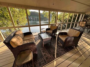 A covered outdoor seating area with wicker furniture and a view of a lake. - Warluskee Luxury Lakefront Cottage w/ Hot Tub

 (Waleska)