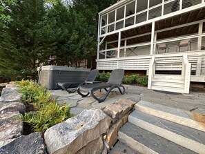 A patio area with outdoor seating, a hot tub, and a building with large windows. - Warluskee Luxury Lakefront Cottage w/ Hot Tub

 (Waleska)