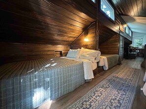 A cozy bedroom with a large bed, wooden walls, and a patterned rug.