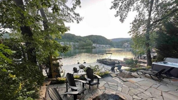 An outdoor patio with stone flooring, a fire pit, and seating areas overlooking a lake. - Warluskee Luxury Lakefront Cottage w/ Hot Tub

 (Waleska)
