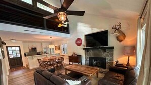 A spacious living room with a fireplace, a dining area, and a kitchen in the background. - Warluskee Luxury Lakefront Cottage w/ Hot Tub

 (Waleska)