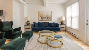 Un salon moderne avec un canapé bleu, des fauteuils verts et une table basse.