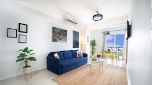 Ein modernes Wohnzimmer mit einem blauen Sofa, einem kleinen runden Tisch und einer Topfpflanze.