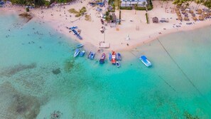 An aerial view of a beach with several boats docked, a sandy shore, and a few buildings in the background. - Tower Condo Pretty Ocean View Boca Chica (Boca Chica)