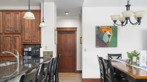 A kitchen with wooden cabinets, a granite countertop, and a dining area with a wooden table and chairs. - Stylish, fully equipped 2-bed / 2-bath condo in Riverstone Village (Coeur d'Alene)