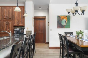 A kitchen with wooden cabinets, a granite countertop, and a dining area with a wooden table and chairs.
