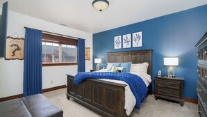 A bedroom with a bed, a nightstand, a dresser, a window with curtains, and wall art. - Stylish, fully equipped 2-bed / 2-bath condo in Riverstone Village (Coeur d'Alene)