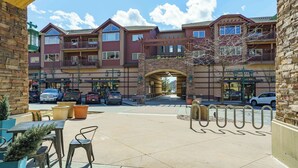 A multi-story hotel with outdoor seating, a stone facade, and a clear sky. - Stylish, fully equipped 2-bed / 2-bath condo in Riverstone Village (Coeur d'Alene)